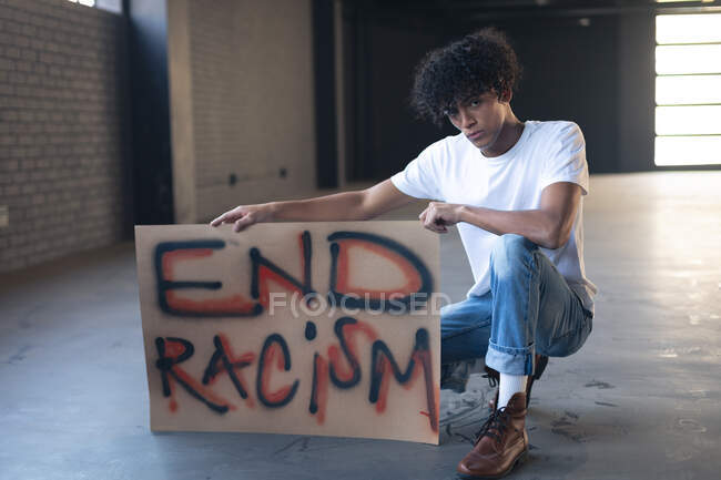 Gemischter Mann mit Protestschild, der in die Kamera blickt. Geschlecht fluid lgbt Identität rassische Gleichberechtigung Konzept. — Stockfoto