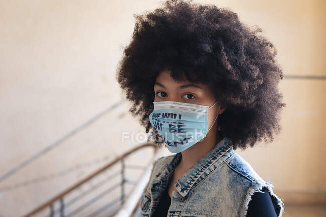 Donna razza mista indossa maschera viso con slogan guardando la fotocamera. genere fluido lgbt identità concetto di uguaglianza razziale. — Foto stock