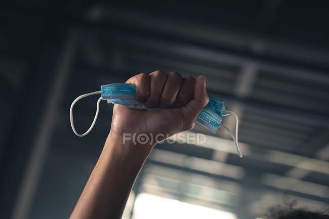 Man in an empty building raising a fist with face mask in it. — Stock Photo