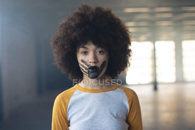 Gemischte Rassenfrau mit einem schwarzen Handabdruck im Gesicht, der in die Kamera schaut. Geschlecht fluid lgbt Identität rassische Gleichberechtigung Konzept. — Stockfoto