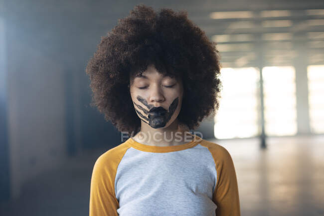 Donna di razza mista con una stampa a mano nera dipinta sul viso. genere fluido lgbt identità concetto di uguaglianza razziale. — Foto stock