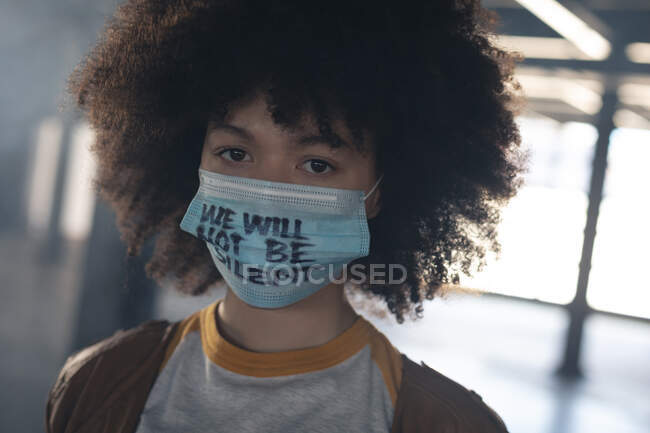 Mixed race woman wearing face mask with slogan looking at the camera. gender fluid lgbt identity racial equality concept. — Stock Photo