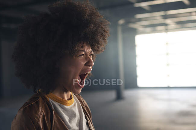 Donna di razza mista in piedi in un edificio vuoto e urlando. genere fluido lgbt identità concetto di uguaglianza razziale. — Foto stock