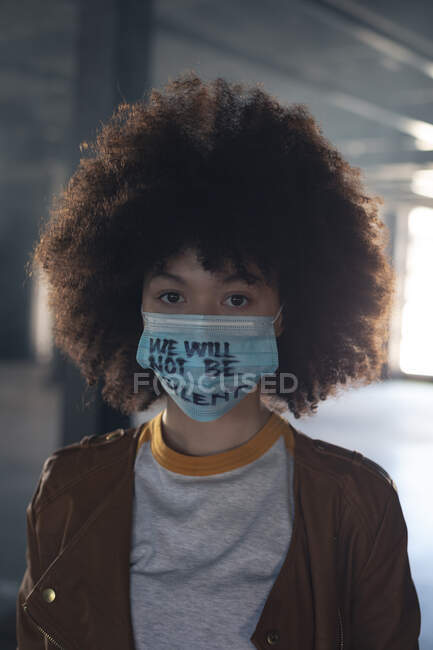 Смешанная расовая женщина в маске с лозунгом, смотрящим в камеру. Концепция гендерного расового равенства. — стоковое фото