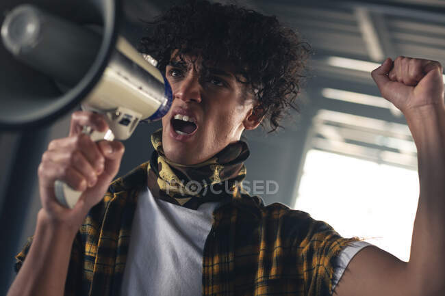 Mixed race man raising hand up shouting in megaphone. gender fluid lgbt identity racial equality concept. — Stock Photo