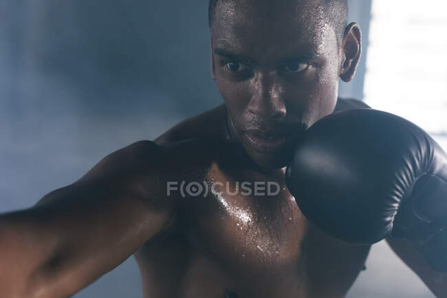 Африканський американець у боксерських рукавицях вдаряє боксерський мішок у порожньому міському будинку. Здоровий спосіб життя в місті. — стокове фото