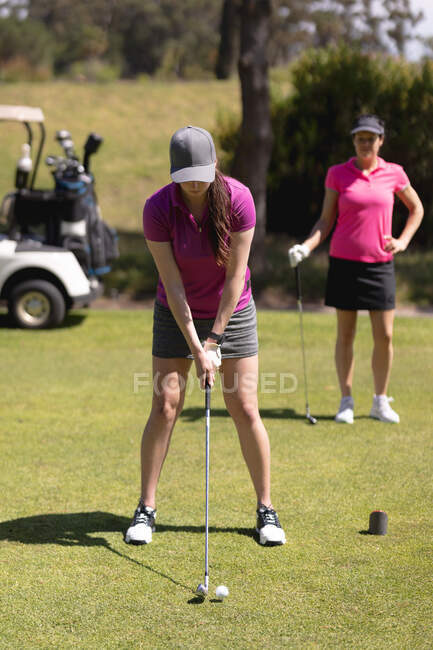 Mujer caucásica practicando golf en el campo de golf en un día soleado brillante. concepto de deporte y estilo de vida activo. - foto de stock