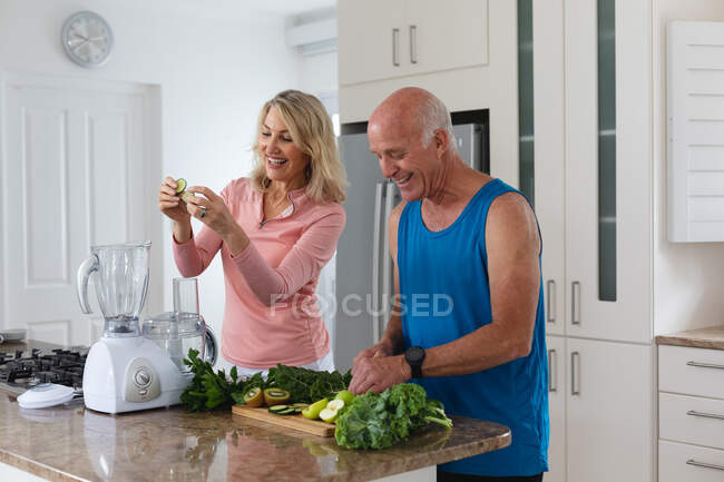 Homem e mulher caucasianos sênior preparando bebidas de saúde de frutas e vegetais. bem-estar fitness na casa de cuidados sênior. — Fotografia de Stock