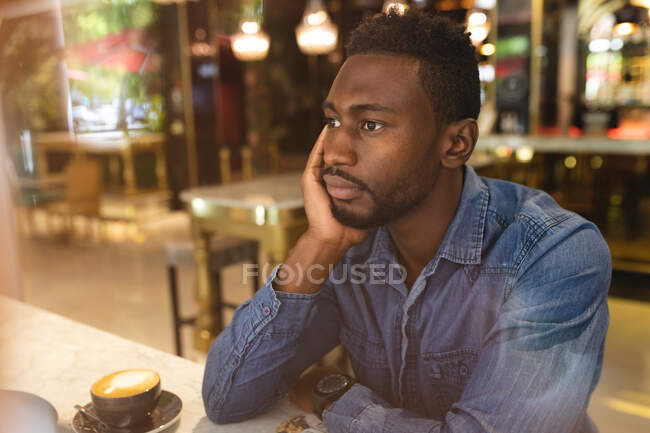 Afroamerikaner sitzt in einem Café und trinkt eine Tasse Kaffee. Geschäftsmann unterwegs in der Stadt. — Stockfoto