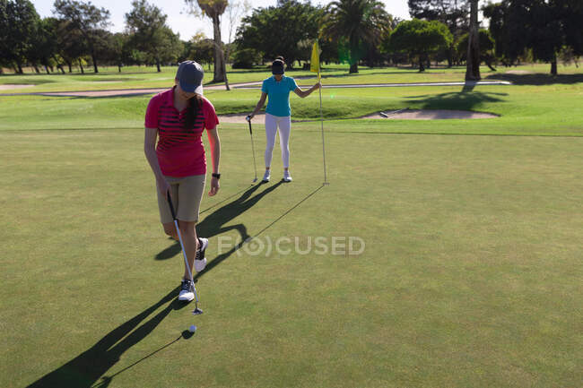 Zwei kaukasische Frauen spielen Golf, eine holt die Fahne aus dem Loch. Sport Freizeit Hobbys Golf gesunder Lebensstil im Freien. — Stockfoto