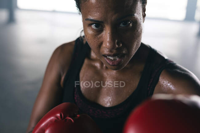 Портрет афро-американської жінки, одягненої в боксерські рукавички, яка б'є боксерський мішок у порожньому міському будинку. Здоровий спосіб життя в місті. — стокове фото