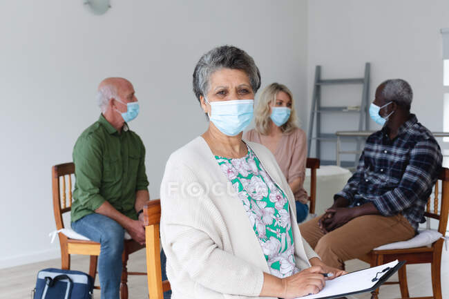 Різні групи літніх людей носять маски для обличчя, які розмовляють під час сеансу групової терапії вдома. здоров'я гігієнічне благополуччя в будинку похилого віку під час пандемії коронавірусу 19 . — стокове фото