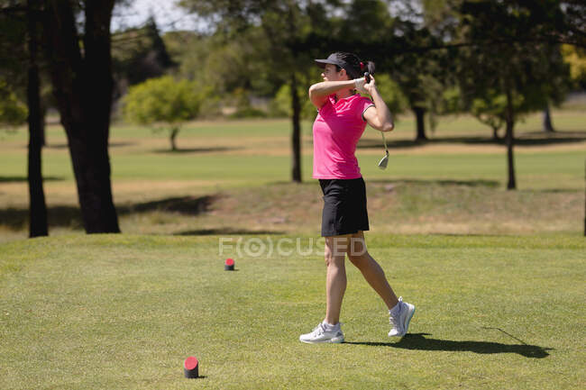 Mujer caucásica practicando golf en el campo de golf en un día soleado brillante. concepto de deporte y estilo de vida activo. - foto de stock