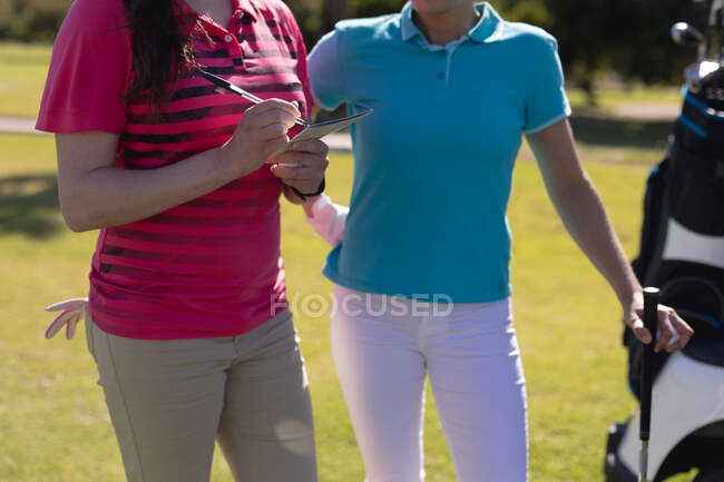 Mittelteil von zwei Frauen, die Golf spielen, eine füllt die Scorecard aus. Sport Freizeit Hobbys Golf gesunder Lebensstil im Freien. — Stockfoto