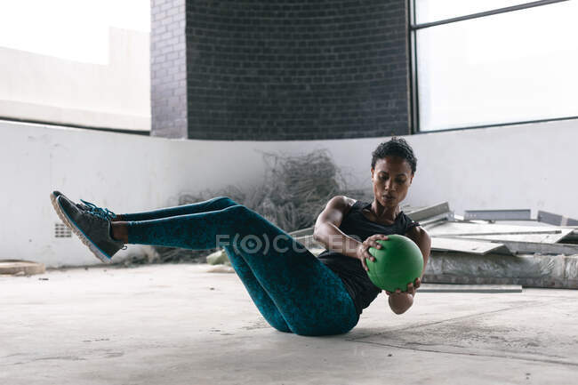 Африканская американка, тренирующаяся с мячом в пустом городском здании. здоровый образ жизни — стоковое фото