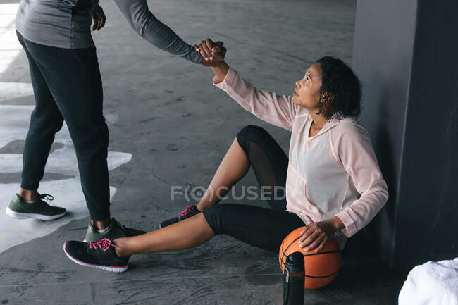 Un uomo afroamericano che aiuta una donna ad alzarsi in un edificio urbano vuoto. fitness urbano stile di vita sano. — Foto stock
