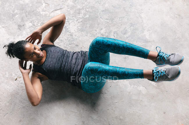 Femme afro-américaine portant des vêtements de sport faisant des craquements dans un bâtiment urbain vide. forme physique urbaine mode de vie sain. — Photo de stock