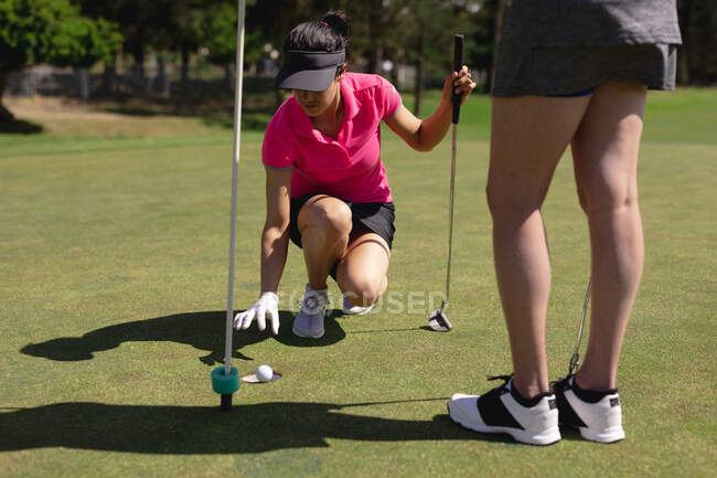 Zwei kaukasische Frauen spielen Golf, einer holt den Ball aus dem Loch. Sport Freizeit Hobbys Golf gesunder Lebensstil im Freien Hygiene während Coronavirus covid 19 Pandemie. — Stockfoto