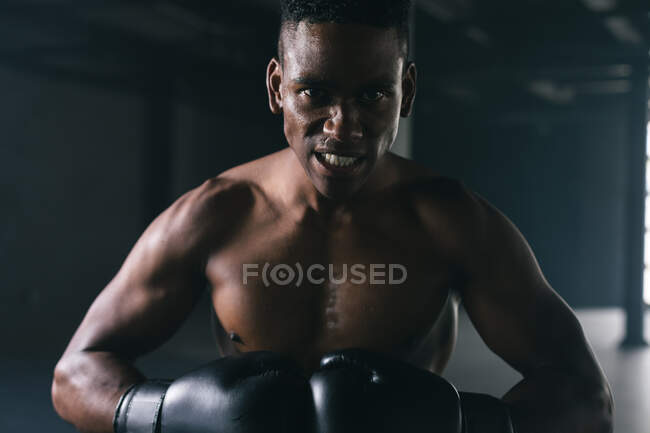 Ritratto di uomo afroamericano che indossa e pugna guanti da boxe in un edificio urbano vuoto. Guardando la telecamera. fitness urbano stile di vita sano. — Foto stock
