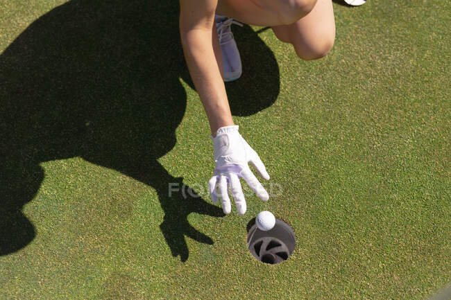 Section basse de la femme jouant au golf laissant tomber une balle dans le trou. loisirs sportifs loisirs golf mode de vie sain en plein air. — Photo de stock