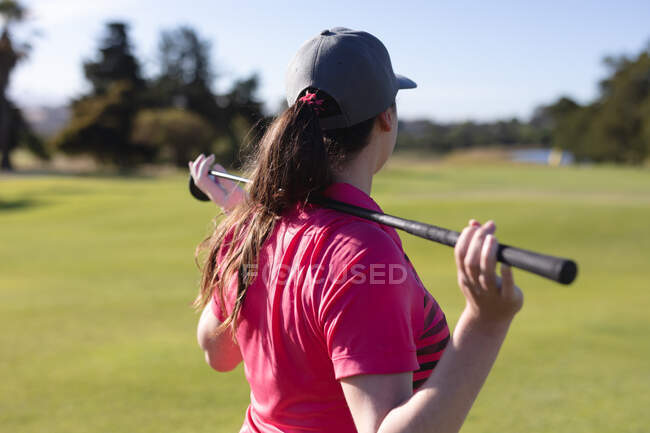 Rear view of caucasian woman on golf course holding golf club across shoulders. sport leisure hobbies golf healthy outdoor lifestyle. — Stock Photo