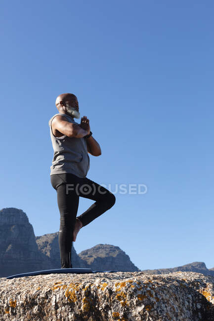 Fit senior african american man standing in pose doing yoga. healthy retirement outdoor fitness lifestyle. — Stock Photo
