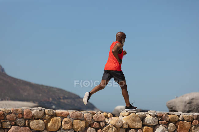 Достатньо дорослий афроамериканець, який біжить прибережною стежкою. здоровий спосіб життя на свіжому повітрі. — стокове фото