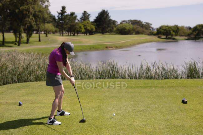 Mujer caucásica jugando al golf club de balanceo y tomando un tiro. deporte ocio aficiones golf estilo de vida al aire libre saludable. - foto de stock
