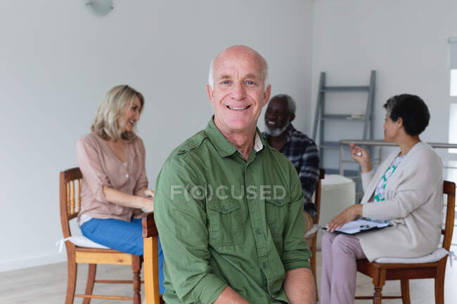 Grupo diverso de idosos conversando durante uma sessão de terapia em grupo em casa. bem-estar fitness na casa de cuidados sênior. — Fotografia de Stock