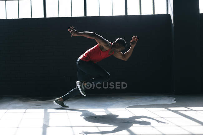 Afrikanischer Mann in Sportkleidung sprintet in einem leeren städtischen Gebäude. urbane Fitness gesunder Lebensstil. — Stockfoto