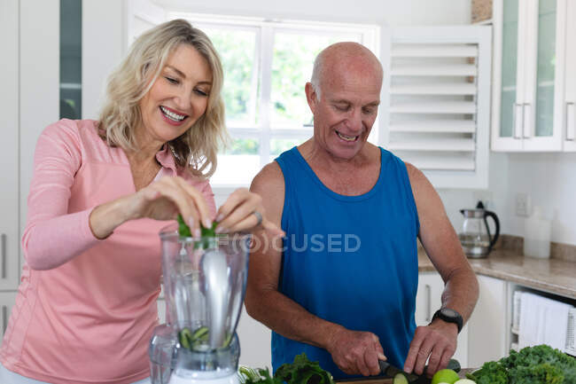 Uomo e donna caucasici anziani che preparano bevande salutari a base di frutta e verdura. salute fitness benessere a casa di cura senior. — Foto stock