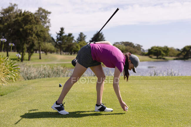 Mulher caucasiana jogando golfe colocando a bola antes de tomar um tiro. esporte lazer hobbies golfe saudável ao ar livre estilo de vida. — Fotografia de Stock