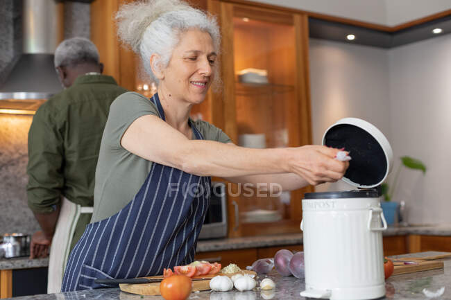 Старшая пара смешанных рас, стоящая на кухне, режет овощи. оставаться дома в изоляции во время карантинной изоляции. — стоковое фото
