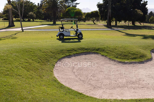 Carrinho de golfe estacionado num campo de golfe perto de um bunker. esporte lazer hobbies golfe saudável ao ar livre estilo de vida. — Fotografia de Stock