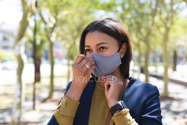 Donna afroamericana che aggiusta la maschera per strada. stile di vita durante il coronavirus covid 19 pandemia. — Foto stock