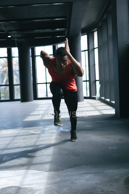 Uomo afroamericano che indossa vestiti sportivi che corrono in un edificio urbano vuoto. fitness urbano stile di vita sano. — Foto stock