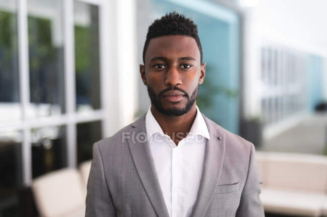 Porträt eines afrikanisch-amerikanischen Geschäftsmannes, der in einem Café steht und in die Kamera blickt. Geschäftsmann unterwegs in der Stadt. — Stockfoto