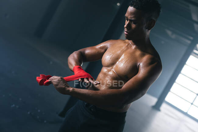 African american boxer taping hands for training in an empty urban building. urban fitness healthy lifestyle. — Stock Photo