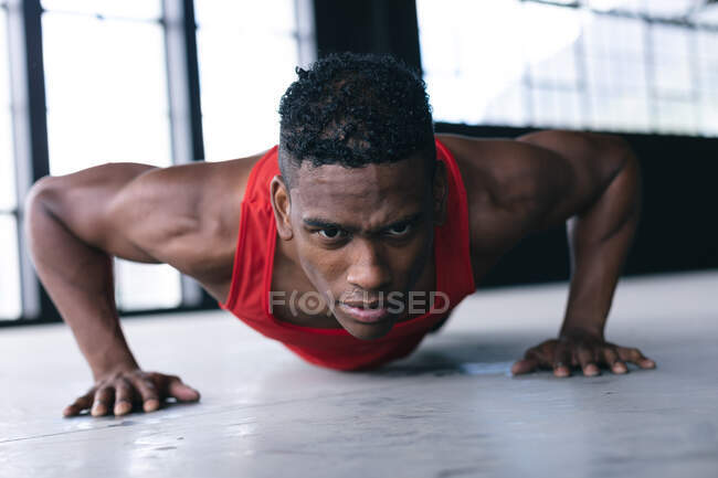 African american man wearing sports clothes doing push ups in empty urban building. urban fitness healthy lifestyle. — Stock Photo