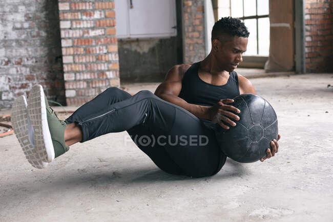 African american man exercising with a medicine ball in empty urban building. urban fitness healthy lifestyle. — Stock Photo