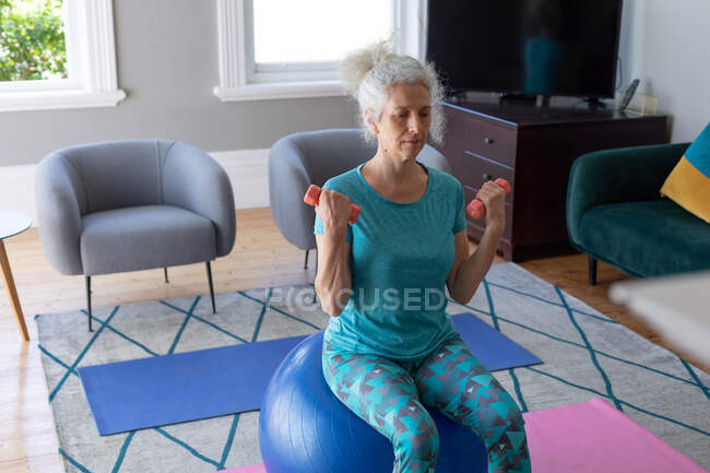 Donna caucasica anziana che indossa vestiti sportivi che si esercitano in soggiorno. stare a casa in isolamento durante l'isolamento in quarantena. — Foto stock