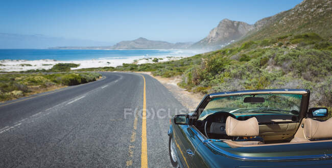 Carro azul vazio ao pé da estrada da montanha perto da costa. viagem de estrada de verão em uma estrada rural pela costa. — Fotografia de Stock