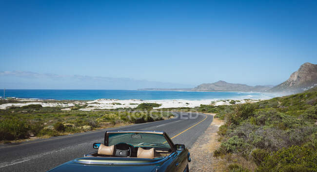 Пустой синий автомобиль, стоящий у горной дороги у берега. летняя поездка по сельской дороге на побережье. — стоковое фото