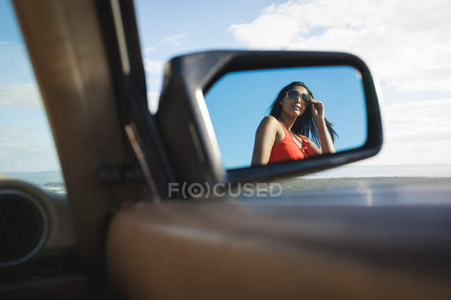 Mulher de raça mista em dia ensolarado refletindo em um espelho. Viagem de estrada de verão em uma estrada rural pela costa. — Fotografia de Stock