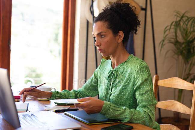 Mujer caucásica usando laptop trabajando desde casa. Permanecer en casa en aislamiento durante el bloqueo de cuarentena. - foto de stock