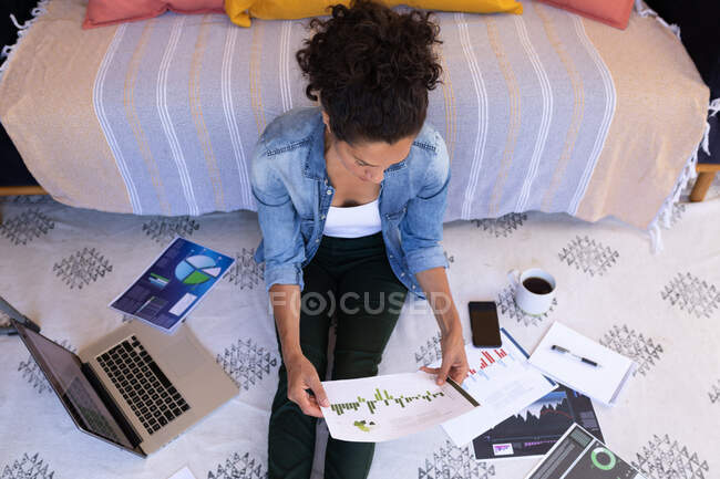 Caucasian woman sitting on floor holding documents, working from home. staying at home in self isolation during quarantine lockdown. — Stock Photo