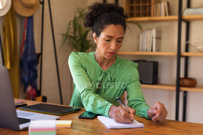 Кавказька жінка сидить за столом, працює з дому, пише. Перебуваючи вдома в ізоляції під час карантину.. — стокове фото