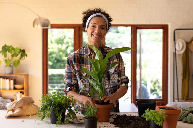 Усміхнена біла жінка розводить рослини вдома. Перебування вдома в самоізоляції під час карантину . — стокове фото