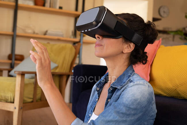 Caucasian woman wearing vr headset sitting on floor at home. Staying at home in self isolation during quarantine lockdown. — Stock Photo