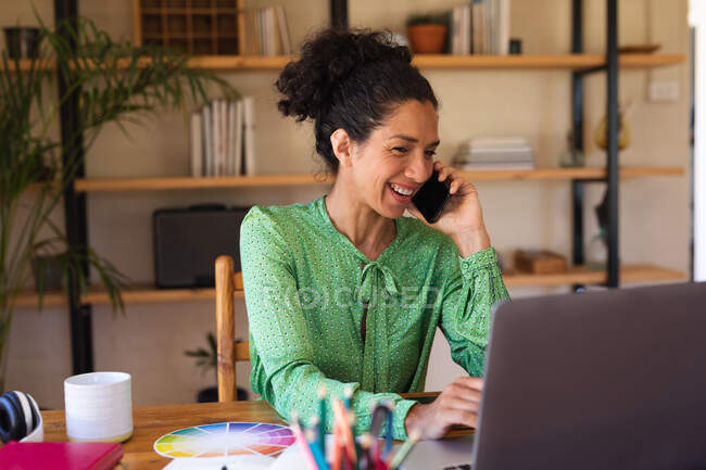 Mujer caucásica hablando en smartphone, trabajando desde casa. Permanecer en casa en aislamiento durante el bloqueo de cuarentena. - foto de stock